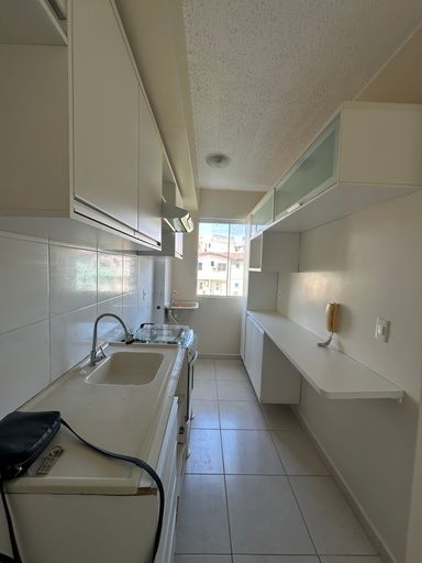 Perspectiva da cozinha ressaltando a distribuição inteligente dos armários e a integração com a área técnica de serviços no Bairro Aeroclube, em Porto Velho-RO.