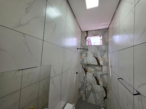 Área de banho revestida do piso ao teto em casa no bairro Conceição, zona sul de Porto Velho, com acabamento moderno, nicho e revestimento decorativo em destaque.