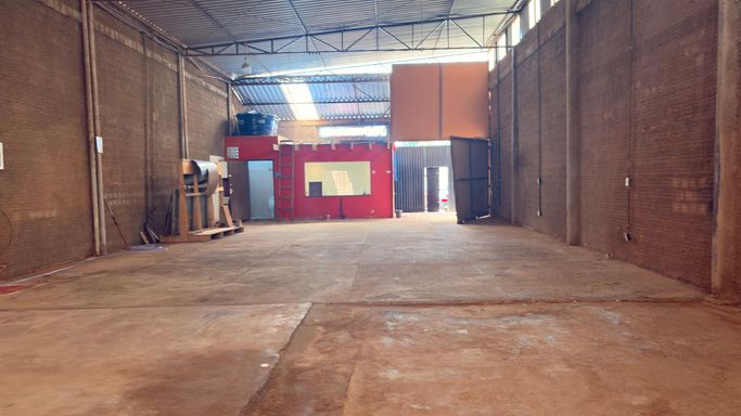 Vista interna evidenciando a setorização administrativa ao fundo e portões metálicos de grande porte para acesso de veículos de carga no Bairro Lagoinha, em Porto Velho-RO.