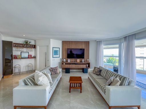 Sala de TV com sofás listrados
Sala de estar com dois sofás dispostos em paralelo e painel de TV em madeira.
Esta confortável sala de TV  exibe dois sofás de tecido claro com padronagem listrada discreta dispostos de frente um para o outro, centralizados por uma mesa de centro de madeira maciça. Ao fundo, destaca-se um elegante painel de TV em madeira de tom quente. A iluminação natural entra pela grande porta de correr que dá acesso à varanda, harmonizando-se com o piso de porcelanato claro e criando um ambiente acolhedor, arejado e elegante.
