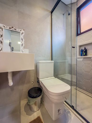 Banheiro com box de vidro

Banheiro com box de vidro temperado e bancada em mármore.

Este banheiro apresenta uma distribuição funcional e moderna. A bancada é em mármore creme com cuba de sobrepor branca e torneira cromada. O vaso sanitário é branco, e o box é delimitado por portas de vidro temperado transparente com esquadrias escuras. O revestimento das paredes combina azulejos cinza claro com detalhe em pastilhas hexagonais dentro do box. O piso é em porcelanato cinza. A iluminação é suave, com pontos de luz embutidos no teto. O ambiente é limpo e sofisticado, com uma estética contemporânea.