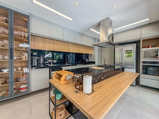 Cozinha planejada com ilha central

Cozinha moderna com ilha central em madeira clara e bancada escura.

A cozinha planejada exibe um design moderno e funcional, com destaque para a ilha central em madeira clara com bancada em granito escuro. O ambiente apresenta armários embutidos em tons de bege e preto, com nichos decorativos em madeira. Os eletrodomésticos em aço inox, como a geladeira e o micro-ondas, garantem modernidade. O piso é em porcelanato cinza, e as paredes são brancas. A iluminação é suave, com pontos de luz embutidos no teto e fitas de LED sob os armários. O ambiente é limpo e sofisticado, com uma estética contemporânea.