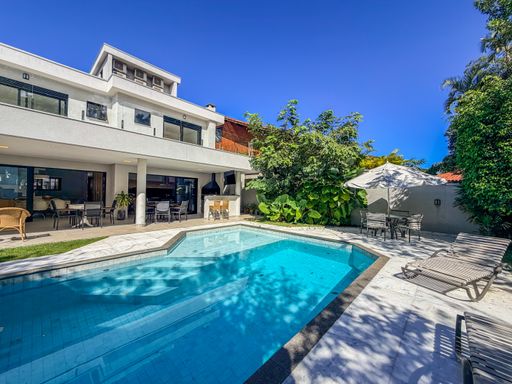 Fachada com piscina

Fachada de casa moderna com piscina e jardim arborizado.

A fachada de casa moderna exibe um design sofisticado, com volumes geométricos e materiais nobres como madeira, vidro e alvenaria branca. A piscina retangular com revestimento em pastilhas azuis está rodeada por deck de madeira e jardim arborizado. O ambiente transmite elegância e conforto.