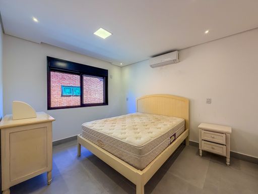 Quarto com cama de casal

Quarto de casal com cama queen e mobiliário em madeira clara.

O quarto de casal exibe um design aconchegante e funcional, com destaque para a cabeceira da cama em madeira clara com ripas horizontais. A cama queen está arrumada com lençóis claros e colcha texturizada. O mobiliário inclui uma cômoda alta em madeira e metal no canto, uma mesa de cabeceira pequena e um criado-mudo. O piso é em laminado de madeira, e as paredes são brancas. A janela com esquadria escura oferece vista para o exterior e possui persiana integrada. A iluminação é suave, com um ponto de luz central no teto. O ambiente transmite tranquilidade e conforto térmico.