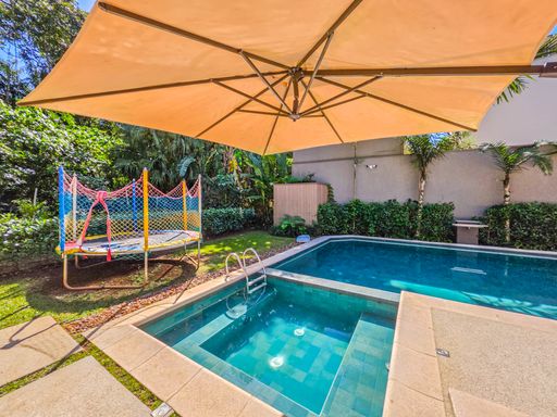 Piscina e área de recreação

Área de piscina infantil integrada a jardim com cama elástica lateral.

O projeto de lazer inclui uma seção de piscina mais rasa, ideal para crianças, adjacente à piscina principal. No jardim lateral, observa-se uma cama elástica, indicando um espaço voltado para a diversão familiar. O paisagismo utiliza palmeiras e arbustos para garantir privacidade sem bloquear a vista do céu. A estética é lúdica e organizada, com uma sensação térmica agradável promovida pela abundância de áreas verdes e água.