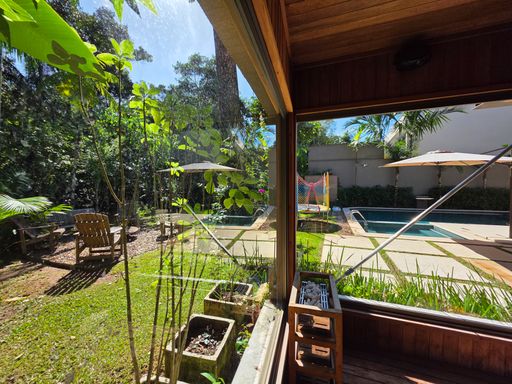 Vista do jardim a partir da sauna

Janela de vidro da sauna enquadrando vegetação e área de lazer.

Esta perspectiva mostra como o interior de madeira da sauna conecta-se visualmente com o jardim tropical e a piscina. A estrutura de vidro permite que a luz natural penetre suavemente no ambiente aquecido. No exterior, observa-se o deck de madeira e a piscina azul brilhante cercada por árvores. A estética é de integração total entre saúde e natureza, proporcionando uma experiência sensorial de relaxamento visual enquanto se usufrui do calor interno.