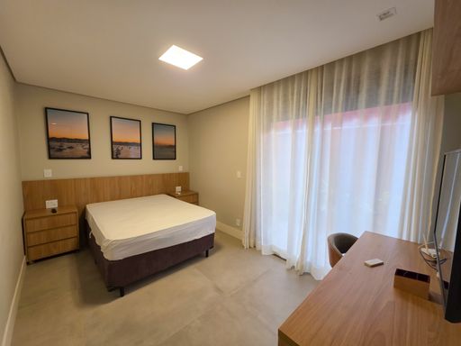 Dormitório principal arejado

Quarto de casal mobiliado com cama queen, enxoval branco e cortinas fluidas.

Este dormitório destaca-se pela luminosidade e simplicidade elegante, com uma cama de casal posicionada entre mesas de cabeceira de madeira. Cortinas de tecido leve emolduram a grande porta de correr que dá acesso a uma varanda. Um trio de telas com fotografias de praia adorna a parede da cabeceira, reforçando o clima litorâneo. O ambiente transmite uma estética de tranquilidade e frescor, com sensação térmica de ventilação natural constante e conforto absoluto.