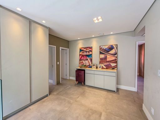 Hall de distribuição superior

Corredor interno com rouparia planejada e portas de acesso aos quartos.

O pavimento superior organiza-se através de um corredor mobiliado com armários planejados brancos e bancada de apoio. Duas telas com arte urbana vibrante trazem personalidade às paredes de tons neutros. A iluminação por spots embutidos no teto garante claridade uniforme por todo o espaço de circulação. A estética é minimalista e funcional, transmitindo uma sensação de ordem e conforto térmico constante entre os aposentos íntimos da residência.