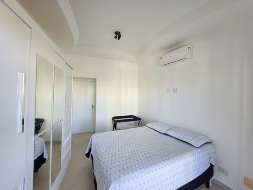 Quarto casal com guarda-roupa espelhado.

Dormitório branco com cama de casal e armário de espelho.

Este quarto destaca-se pelo grande guarda-roupa com portas de correr totalmente espelhadas, uma solução inteligente para ampliar visualmente o espaço reduzido. A cama de casal está posicionada centralmente, com um berço portátil ao lado, indicando versatilidade para famílias. O ar-condicionado Split está instalado para máximo conforto. A iluminação de teto moderna e as paredes brancas mantêm a estética limpa e sofisticada, proporcionando um refúgio térmico acolhedor e tranquilo dentro do apartamento.