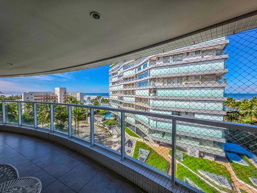 Varanda com vista para o mar  da Riviera de São Lourenço.

Sacada de apartamento com rede de proteção e vista para edifícios e oceano.

Esta varanda espaçosa oferece uma vista panorâmica para o mar, emoldurada por uma rede de proteção de malha fina para máxima segurança. O guarda-corpo combina alumínio e vidro, permitindo a passagem plena da luz natural que ilumina o piso cerâmico em tons neutros. Ao fundo, observa-se a arquitetura moderna dos edifícios vizinhos e um paisagismo tropical com gramados verdes vibrantes, criando uma estética de lazer e tranquilidade. A sensação térmica é de frescor constante devido à proximidade com a orla.