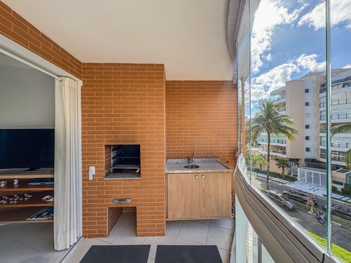 Churrasqueira privativa na sacada

Área gourmet compacta com churrasqueira em tijolinho e bancada de granito.

Este detalhe da varanda destaca a churrasqueira integrada, construída com tijolos aparentes em tom ocre, harmonizando com o revestimento da parede. Ao lado, uma bancada funcional em granito escuro com pia e armário inferior em madeira clara otimiza o preparo de alimentos. O piso cerâmico é resistente e fácil de manter, enquanto a abertura lateral garante a ventilação necessária. O ambiente é prático e convidativo para momentos de lazer gastronômico em um cenário urbano litorâneo.