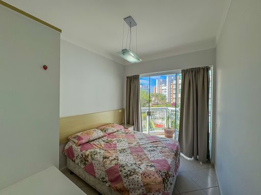 Suíte master aconchegante com varanda

Quarto de casal com cama ampla, enxoval floral e acesso à sacada privativa.

O dormitório principal exibe uma atmosfera de relaxamento com uma cama de casal vestida com colcha floral em tons de rosa e verde. A cabeceira em madeira clara integra-se à parede lateral, onde se encontra um criado-mudo coordenado. Uma moderna luminária pendente de cristal sobre a cama adiciona um toque de sofisticação. As cortinas em tom fendi emolduram a porta de vidro que dá acesso à varanda, permitindo o controle da luz e ventilação natural. A sensação térmica é de extremo conforto e privacidade.