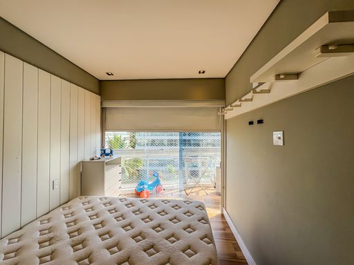 Quarto com vista externa

Dormitório iluminado com cama de casal e sacada integrada.

Este quarto destaca-se pela abundante entrada de luz natural vinda da sacada envidraçada. A cama de casal está posicionada lateralmente ao painel de TV planejado. A marcenaria branca e o piso de madeira clara ampliam a claridade do ambiente, transmitindo uma estética arejada e fresca. Cabideiros metálicos fixados na parede lateral oferecem praticidade para o dia a dia. A integração com o exterior através do vidro traz vivacidade ao cômodo, resultando em um espaço termicamente ventilado e visualmente clean.
