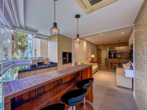 Varanda integrada vista da sala

Varanda gourmet com banquetas escuras e churrasqueira vista de dentro do apartamento.

Perspectiva de transição fluida entre a sala de estar interna e o ambiente da varanda gourmet. O alinhamento dos móveis, incluindo a bancada de madeira com as banquetas pretas e a pia embutida de granito preto, demonstra a otimização de espaço do projeto arquitetônico. A iluminação combina lâmpadas de LED frias embutidas com o aconchego dos pendentes aramados, resultando em uma estética urbana moderna, limpa e perfeitamente integrada para receber amigos e familiares.