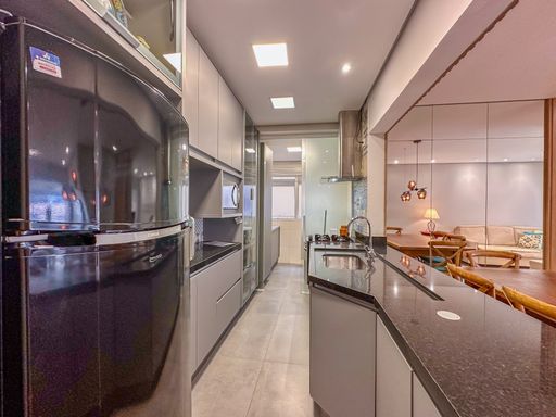 Cozinha em estilo corredor integrada

Corredor de cozinha com móveis cinzas, bancada escura e cooktop de indução.

Perspectiva linear da cozinha planejada integrada em estilo corredor, destacando o fluxo de trabalho ergonômico. A bancada de granito preto estende-se para abrigar um cooktop de indução moderno com botões frontais. O revestimento das paredes e os armários planejados superiores em tons claros geram um contraste limpo e minimalista com a pedra escura. A abertura frontal conecta visualmente a cozinha com a área de jantar, promovendo um ambiente social leve, funcional e de estética contemporânea impecável.