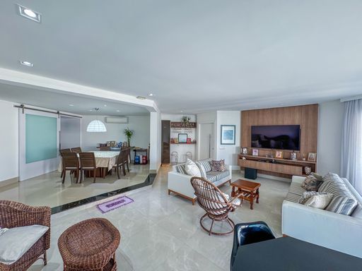 Sala de estar e jantar conjugadas
Visão ampla da sala integrada mostrando sofás, poltronas de fibra e sala de jantar.
Esta perspectiva engloba toda a área social do apartamento, evidenciando a transição suave entre a sala de TV, o espaço de leitura com poltronas de fibra sintética marrom e a mesa de jantar ao fundo. O painel de madeira na parede da TV contrasta de forma elegante com as paredes brancas e o piso de porcelanato brilhante. A iluminação bem distribuída e os móveis planejados conferem sofisticação, excelente circulação e uma agradável sensação de amplitude.