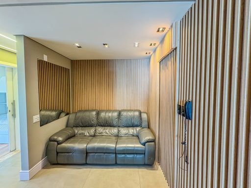 Home theater aconchegante

Visão frontal de sofá de couro cinza contra parede ripada.

O destaque desta sala é o conforto proporcionado pelo sofá de três lugares em couro cinza, emoldurado por um elegante painel ripado de madeira clara. No teto, spots direcionáveis embutidos garantem uma iluminação funcional e cênica. Uma parede em tom fendi ao fundo abriga um espelho vertical, que auxilia na sensação de amplitude do cômodo. O uso de materiais como madeira natural e couro sintético reforça a estética de design moderno, proporcionando um ambiente termicamente confortável para o descanso.