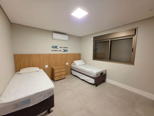 Quarto de hóspedes planejado

Dormitório mobiliado com duas camas de solteiro e marcenaria amadeirada.

O quarto de solteiro ou hóspedes dispõe de duas camas individuais com colchas claras e uma mesa de cabeceira central em madeira. Janelas amplas com esquadrias escuras permitem a entrada controlada de luz e ventilação natural. O piso cerâmico acetinado reforça a higiene e a praticidade do ambiente. A estética é limpa e funcional, com uma sensação térmica equilibrada graças ao uso de madeira nas paredes e sistema de climatização embutido.