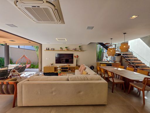 Living com adega lateral

Sala de estar com vista para o espaço gourmet e adega ao fundo.

A sala de estar, mobiliada com sofá modular, foca na convivência social. Ao fundo, a escada de madeira flutuante e a adega integrada sob os degraus adicionam um toque arquitetônico refinado. Um sistema de ar-condicionado cassete embutido no teto garante o controle térmico ideal para o amplo espaço. A transição para o terraço coberto e a piscina cria uma estética de "indoor-outdoor living", onde a luz e a natureza fazem parte da decoração interna.