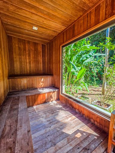 Sauna seca panorâmica

Interior de sauna revestida em madeira com ampla janela para o jardim.

A sauna seca é inteiramente revestida com réguas de madeira clara, dispondo de bancos em diferentes níveis. O diferencial é uma grande janela de vidro que oferece uma vista relaxante para a vegetação tropical externa. A iluminação é suave e embutida nos bancos, valorizando a textura da madeira. O ambiente transmite uma estética de puro bem-estar e luxo, onde a sensação térmica de calor controlado é equilibrada visualmente pelo verde do exterior.