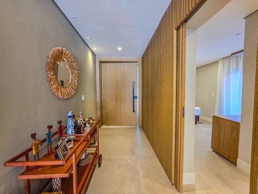 Hall de entrada decorado

Corredor com aparador de madeira, adornos e porta pivotante ripada.

O hall de entrada apresenta uma porta pivotante imponente revestida em ripas de madeira clara. Um aparador de madeira abriga objetos decorativos como esculturas coloridas e uma guirlanda natural na parede. O piso de porcelanato neutro estende-se por todo o corredor, que é iluminado por luz indireta. A estética é de boas-vindas sofisticada, utilizando elementos naturais para criar uma transição térmica e visual entre o exterior e o interior da residência.