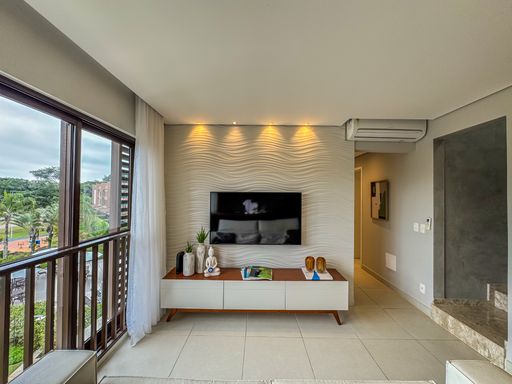 Sala de Estar Integrada

Ambiente de estar integrado com mesa de jantar e sofá claro.

Amplo espaço social integrado unindo a sala de estar em primeiro plano e a área de jantar ao fundo. O mobiliário inclui um sofá de tecido claro posicionado em frente a um rack de madeira com TV de tela plana. O piso cerâmico claro unifica visualmente os ambientes, revestidos com paredes em tom fendi. O projeto de iluminação traz sancas de gesso e pendentes decorativos, resultando em uma estética arejada, fresca e perfeita para o convívio familiar.