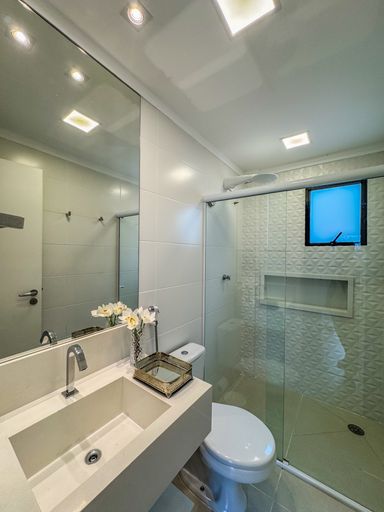 Banheiro Social Clean

Banheiro com pia de mármore e box de vidro transparente.

Um banheiro moderno e funcional revestido com azulejos claros nas paredes e piso cerâmico branco. Conta com uma bancada de mármore com cuba embutida, armário planejado inferior na cor branca e espelho retangular instalado na parede. O box possui fechamento em vidro temperado transparente, mantendo a sensação de amplitude. A iluminação é clara e direta, reforçando a estética de higiene, organização e frescor do cômodo.