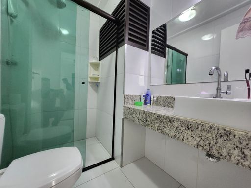 Banheiro com box de vidro

Banheiro moderno com box de vidro verde, vaso sanitário e bancada de granito.

Banheiro social funcional com área do box delimitada por portas de vidro temperado em tom esverdeado e esquadrias pretas. A bancada é esculpida em granito ornamental salpicado, trazendo uma textura natural ao espaço, e conta com uma cuba de apoio branca e torneira metálica cromada. Acima da bancada, um espelho retangular amplo amplia visualmente o ambiente. O vaso sanitário branco está posicionado na lateral esquerda. O revestimento cerâmico e a iluminação embutida reforçam a sensação de asseio e modernidade.