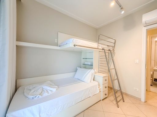 Quarto com camas integradas em marcenaria

Quarto planejado mostrando camas e armário ripado de madeira clara.

Perspectiva interna do quarto multifuncional, evidenciando o mobiliário planejado em madeira clara e texturas lineares. A cama de solteiro inferior é arrumada com enxoval branco impecável e toalha decorativa. A estrutura do beliche superior estende-se acima com uma cabeceira em painel ripado que adiciona textura e design moderno ao espaço. O piso cerâmico claro reflete a iluminação embutida do teto. O quarto transmite uma sensação de organização milimétrica, limpeza e aproveitamento inteligente, sendo ideal para acomodar visitas ou familiares com máximo conforto.