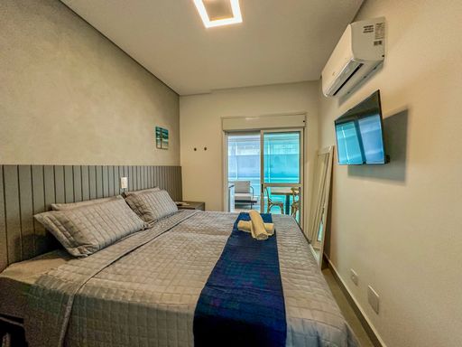 Dormitório com porta para varanda.

Cama de casal com cabeceira ripada e acesso para sacada envidraçada.

Este ângulo do quarto destaca a porta de correr de vidro que dá acesso direto à varanda, proporcionando excelente ventilação e luminosidade. A cabeceira ripada cinza integra-se às paredes em cimento queimado, mantendo o estilo contemporâneo. A disposição é otimizada para o descanso, com luminárias embutidas que criam um clima aconchegante. A estética é minimalista e funcional, ideal para quem busca praticidade e conforto no dia a dia.
