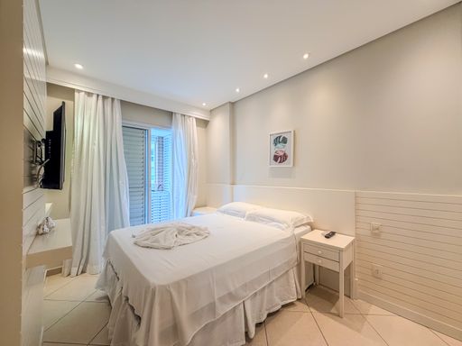 Quarto de casal com cabeceira estofada

Quarto de casal com cama queen, lençóis brancos e painel decorativo na parede.

Quarto de casal master refinado e aconchegante, configurado com uma cama de casal padrão queen disposta com enxoval de algodão branco e colcha trabalhada. A parede da cabeceira exibe um painel de marcenaria branca texturizada com frisos horizontais e criado-mudo suspenso integrado de cada lado. Acima da cama, uma pequena tela decorativa minimalista traz um toque de cor. Cortinas de tecido encorpado bege bloqueiam a luz da janela ou porta-balcão. O teto rebaixado em gesso conta com iluminação embutida perimetral por spots de LED, promovendo um conforto visual repousante e sensação térmica agradável.
