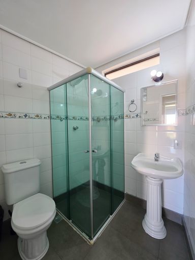Banheiro social com box vidro.

Banheiro com revestimento cerâmico branco e box de vidro verde.

Um banheiro social impecável, totalmente revestido com azulejos brancos e uma faixa decorativa em mosaico azul e verde. O box de vidro temperado esverdeado protege a área do chuveiro, mantendo a organização. A louça sanitária é branca e de design clássico, com metais cromados de alta qualidade. O espelho acima da pia amplia o ambiente, que conta com iluminação branca direta. A estética foca na higiene e praticidade, proporcionando uma sensação térmica de frescor e limpeza constante.