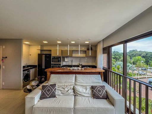 Sala de Jantar Conjugada

Mesa de jantar retangular com cadeiras bege estofadas em sala iluminada.

Uma elegante sala de jantar integrada com design contemporâneo e paleta de cores neutras. O ambiente apresenta uma mesa de jantar de laca clara e brilhante cercada por cadeiras com estofamento texturizado. Ao fundo, avista-se a sala de estar e uma porta de correr de vidro que dá acesso à varanda ensolarada. A iluminação é enriquecida por um moderno lustre pendente esférico acobreado e pontos de luz embutidos no gesso. O piso de porcelanato polido reflete a luminosidade natural, conferindo sofisticação e uma sensação térmica agradável ao espaço.