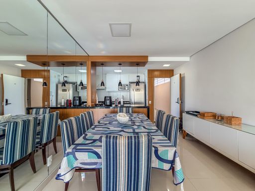 Sala de jantar com espelho

Mesa de jantar com cadeiras listradas em frente a parede espelhada.

Uma área de jantar elegante composta por uma mesa robusta e cadeiras estofadas com padronagem listrada em azul e branco. A parede lateral é inteiramente coberta por um espelho, que amplia visualmente o ambiente e reflete a iluminação pendente sobre o balcão da cozinha americana. O uso de madeira clara nos móveis e o piso brilhante conferem uma sensação de amplitude e requinte, ideal para refeições em família em um cenário moderno.