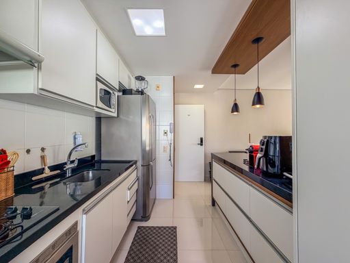Cozinha americana planejada

Cozinha estreita com armários brancos e bancadas de granito escuro.

Uma cozinha moderna em estilo corredor, equipada com armários aéreos brancos e bancadas em granito preto absoluto. A iluminação é garantida por spots no teto e pendentes pretos sobre o balcão de refeições rápidas. Eletrodomésticos em aço inox, como a geladeira e o micro-ondas, completam a funcionalidade do espaço. A organização impecável e o contraste entre o branco e o preto criam uma estética industrial-suave e urbana.