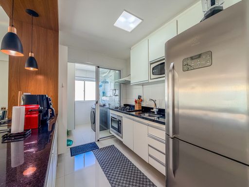 Cozinha integrada à lavanderia

Vista funcional da cozinha com acesso à área de serviço.

Este ângulo mostra a continuidade da cozinha planejada em direção à lavanderia, separada por uma porta de vidro. A bancada de granito abriga um cooktop moderno e uma cuba de inox, com revestimento de azulejos brancos nas paredes para facilitar a limpeza. O piso cerâmico claro e a iluminação central em LED garantem um ambiente de trabalho bem iluminado e funcional. A sensação térmica é de frescor e organização doméstica eficiente.