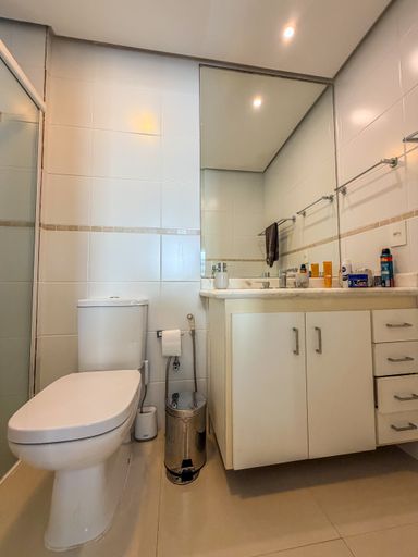 Banheiro privativo da suíte

Banheiro com bancada branca, armário inferior e espelho amplo.

O banheiro da suíte é equipado com uma bancada de material sintético branco e gabinete de madeira planejado. O amplo espelho reflete o box de vidro e o revestimento cerâmico das paredes, criando uma sensação de limpeza e amplitude. Detalhes como o porta-toalhas cromado e a iluminação embutida completam o design funcional. A estética é clean e prática, focada no conforto cotidiano.