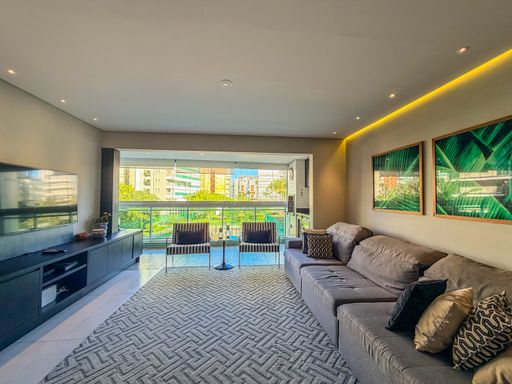 Living amplo com vista externa

Sala de estar iluminada com acesso à varanda e decoração contemporânea.

A sala de estar exibe um layout aberto e bem iluminado, conectando-se diretamente à varanda envidraçada. O mobiliário inclui um extenso sofá cinza e um rack linear em tom escuro. Elementos como o tapete geométrico e as almofadas em tons de dourado e preto adicionam textura e sofisticação. A iluminação em trilhos e sancas de LED destaca as cores neutras das paredes, transmitindo uma sensação térmica equilibrada e uma estética residencial de alto padrão.Cozinha planejada estilo corredor

Cozinha moderna com armários pretos, bancada de granito e eletrodomésticos inox.