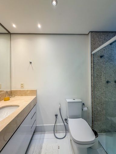 Banheiro privativo da suíte

Banheiro com pia de mármore e área de banho integrada.

O banheiro da suíte segue a estética clean com bancada em mármore creme e armários brancos inferiores. O box de vidro transparente integra a área de banho, que possui revestimento em pastilhas e nicho embutido. A iluminação clara e o amplo espelho garantem funcionalidade e higiene visual. Materiais nobres como pedra e metal cromado reforçam o padrão de qualidade do acabamento.