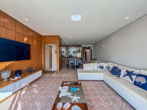 Sala de estar temática marinha

Living amplo com sofá branco e painel de madeira.

Esta sala de estar sofisticada combina o conforto de um grande sofá em L branco com detalhes decorativos de estrelas-do-mar em tons de azul. O painel de TV em madeira natural aquece o ambiente, criando um contraste elegante com o tapete de padronagem geométrica cinza. A mesa de centro exibe objetos náuticos, reforçando o estilo litorâneo. A iluminação é suave, proveniente de spots embutidos, resultando em uma estética acolhedora e luxuosa para recepções.