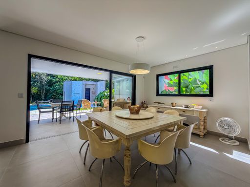 Sala de jantar integrada à varanda

Mesa de jantar de madeira para dez pessoas integrada à varanda.

Esta sala de jantar sofisticada apresenta uma grande mesa de madeira maciça com tampo em mármore creme, acompanhada por dez cadeiras estofadas em linho bege. O ambiente é integrado à varanda por meio de portas de correr de vidro, que permitem a entrada abundante de luz natural e oferecem vista para o exterior arborizado. O piso é em porcelanato claro, e as paredes são brancas. A iluminação é suave, com pontos de luz embutidos no teto e um pendente central sobre a mesa. O ambiente transmite elegância e conforto.