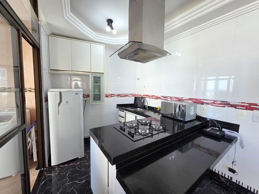 Cozinha americana planejada.

Cozinha moderna com balcão de granito preto e fogão cooktop.

Uma cozinha funcional e estilosa que utiliza o contraste entre o granito preto das bancadas e os armários planejados brancos. O espaço conta com fogão cooktop embutido, coifa em inox e revestimento cerâmico nas paredes com detalhes em mosaico vermelho. A iluminação branca direta garante eficiência para o preparo de refeições. A estética é limpa e organizada, com superfícies brilhantes que refletem a modernidade do imóvel e facilitam a higienização do dia a dia.