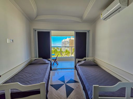 Dormitório de solteiro com vista.

Quarto com duas camas de solteiro e acesso à varanda.

Este dormitório apresenta uma disposição prática com duas camas de solteiro e enxoval em tons de cinza. O diferencial é o acesso direto à varanda através de portas de correr de vidro, permitindo que os moradores acordem com a luz do sol e vista para o mar. O quarto é climatizado com ar-condicionado Split e possui teto de gesso com sancas. O piso marmorizado mantém o padrão do imóvel. A estética é de serenidade e frescor, ideal para o repouso com conforto térmico garantido.