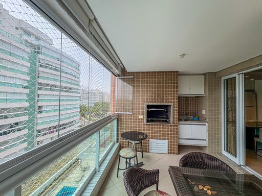 Varanda fechada com vista urbana

Espaço gourmet com churrasqueira, mesa e fechamento de cortina de vidro.

Visão em perspectiva da varanda gourmet mostrando o layout completo de lazer do apartamento. O ambiente dispõe de uma mesa alta redonda com banquetas metálicas próximas ao guarda-corpo de alumínio e vidro, que conta com tela e cortina de vidro retrátil de proteção. Poltronas de fibra sintética escura com almofadas criam um espaço de estar confortável sobre o piso cerâmico claro. Ao fundo, a churrasqueira pastilhada e a pia completam a estrutura, emolduradas pela vista externa de edifícios residenciais modernos sob iluminação natural.