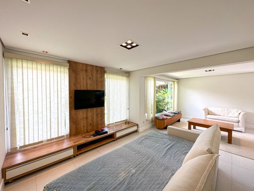 Home theater aconchegante integrado

Sala de TV com grande painel de madeira vertical e cortinas translúcidas.

Este espaço dedicado ao home theater conta com um grande sofá modular cinza-escuro com textura listrada, ideal para momentos de lazer. O destaque do ambiente é o painel de televisão vertical revestido em madeira de tom médio, que se estende do chão ao teto, contrastando com as paredes brancas. Grandes janelas laterais são suavizadas por cortinas de tecido translúcido que filtram a luz solar de forma elegante. O piso de cerâmica clara reflete a luminosidade, mantendo o espaço amplo, sofisticado e acolhedor.