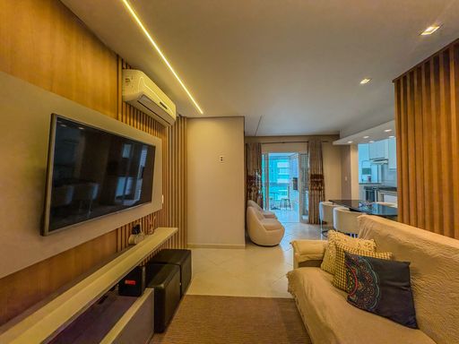 Visão longitudinal dos ambientes integrados

Sala de TV com painel de madeira e abertura para varanda ensolarada.

Ângulo inverso que valoriza a profundidade e a funcionalidade do imóvel. O painel de TV em madeira ripada com televisão preta destaca-se na lateral esquerda sob o fluxo luminoso da fita de LED e do ar-condicionado. O sofá com almofadas coloridas delimita o corredor de circulação que conduz o olhar diretamente para a varanda gourmet ao fundo, onde poltronas confortáveis criam um espaço de contemplação. O design de interiores combina tons amadeirados e tecidos aconchegantes para uma sensação térmica equilibrada e sofisticada.