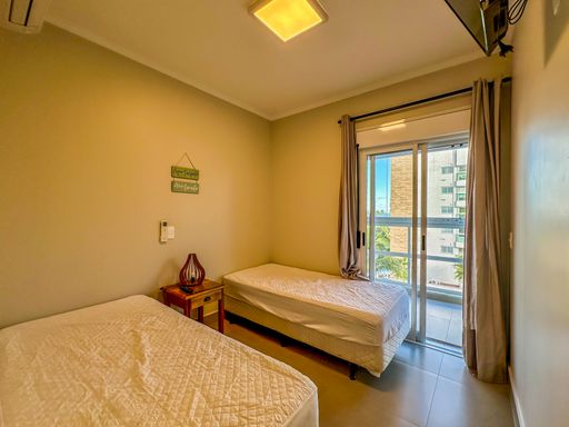 Quarto com duas camas de solteiro

Quarto de hóspedes com duas camas de solteiro paralelas, mesa de cabeceira rústica e porta balcão para a sacada.

Este arejado dormitório de solteiro é configurado com duas camas dispostas paralelamente, cobertas com colchas brancas texturizadas. Entre elas, uma mesa de cabeceira em madeira maciça escura serve de apoio para uma luminária rústica. A parede exibe quadros decorativos em tons de verde com mensagens praianas. O ambiente recebe excelente ventilação natural vindas da ampla porta balcão de alumínio, que conecta o quarto à área externa, criando uma atmosfera fresca, iluminada e praiana.