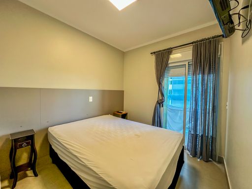 Suíte de casal com varanda

Quarto de casal com cama de casal, cabeceira de parede em dois tons e porta de vidro com acesso à varanda externa.

Este aconchegante dormitório de casal apresenta uma decoração clean com paredes pintadas em tons neutros de bege e marrom claro. A cama box de casal centralizada é vestida com lençol branco liso. Na parede acima da cabeceira, destacam-se pequenos quadros decorativos com temática náutica. O piso cerâmico reflete a luz natural abundante que entra pela grande porta de correr de alumínio branco com vidros transparentes, que dá acesso direto à sacada iluminada, transmitindo uma sensação de amplitude e conforto térmico.