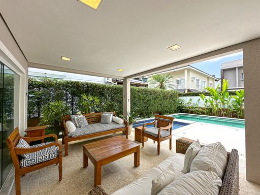 Estar externo sob a varanda

Living externo com sofás de fibra sintética e mesa de centro de madeira.

Um sofisticado lounge de estar foi montado sob a cobertura da varanda, funcionando como uma extensão da sala interna. O mobiliário é composto por sofás e poltronas de fibra sintética com almofadas grossas e confortáveis em tons claros e tecidos náuticos listrados. Uma mesa de centro retangular em madeira serve de apoio central. O espaço é emoldurado por uma densa cerca viva de arbustos ao fundo e oferece vista direta para a piscina ensolarada, combinando o conforto de um living interno com o frescor do ambiente externo.