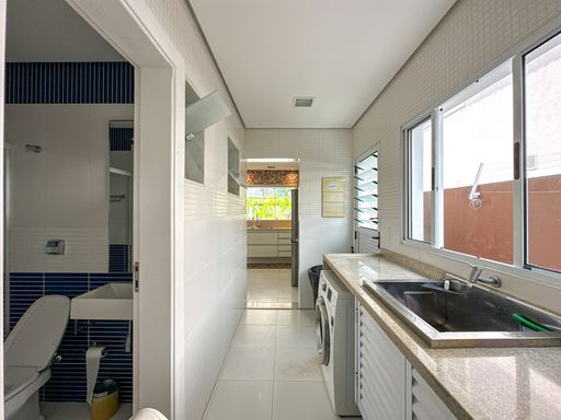 Lavanderia e área de serviço integradas

Corredor de área de serviço com máquina de lavar, tanque de granito e portas brancas.

Esta área de serviço longa e funcional exibe um layout em formato de corredor com piso cerâmico claro e paredes revestidas de azulejos brancos. Uma bancada de granito ocre abriga um tanque embutido de aço inox, posicionada logo acima de uma máquina de lavar roupas de abertura frontal. Janelas de alumínio garantem a circulação de ar necessária para a secagem de roupas. Ao fundo, uma porta de correr conecta o ambiente à cozinha, mantendo a privacidade sem comprometer a fluidez do imóvel.